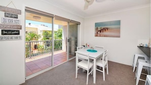 A balcony with a sliding glass door, a ceiling fan, and a table with chairs. - Beautiful 2 Bedroom Retreat  ( 1 min from tramline) (Surfers Paradise)