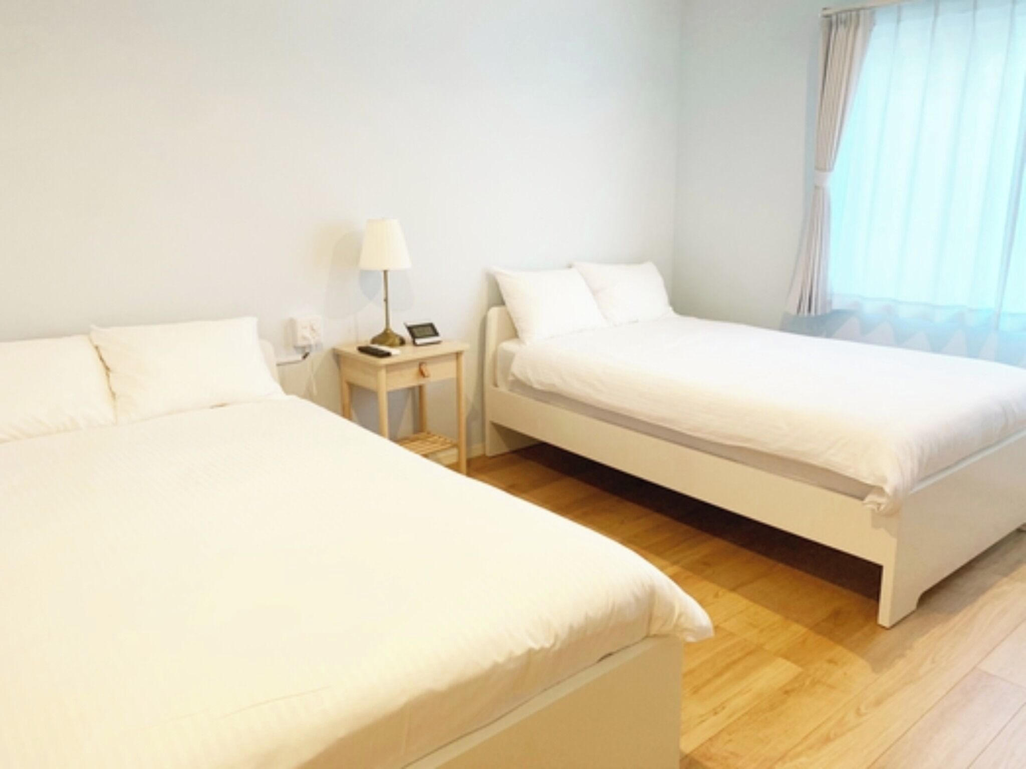 Una habitació d'hotel amb dos llits individuals, una taula de nit amb una làmpada i una finestra amb cortines.