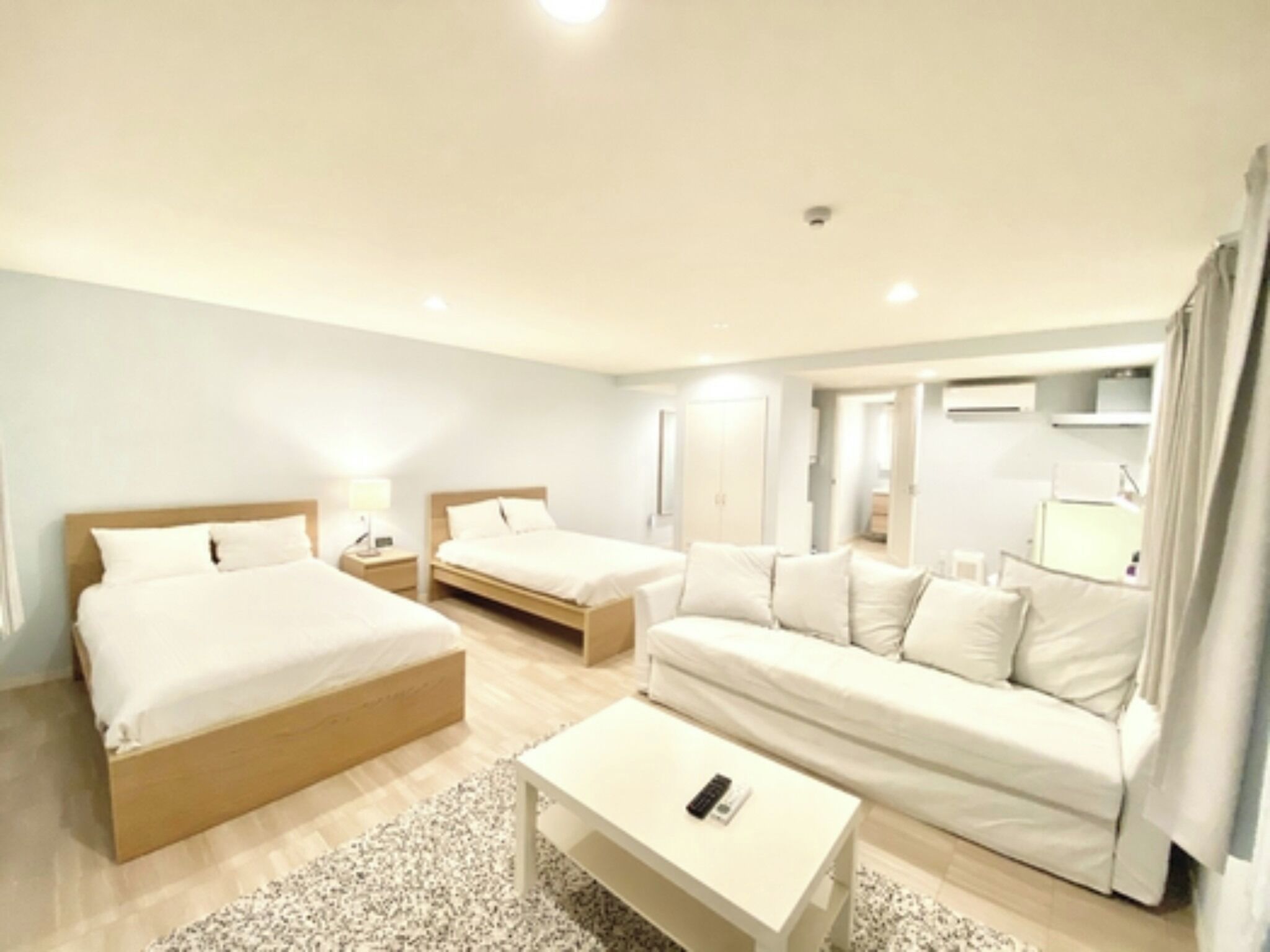 Habitació d'hotel amb dos llits individuals, un sofà, una taula petita i una televisió.