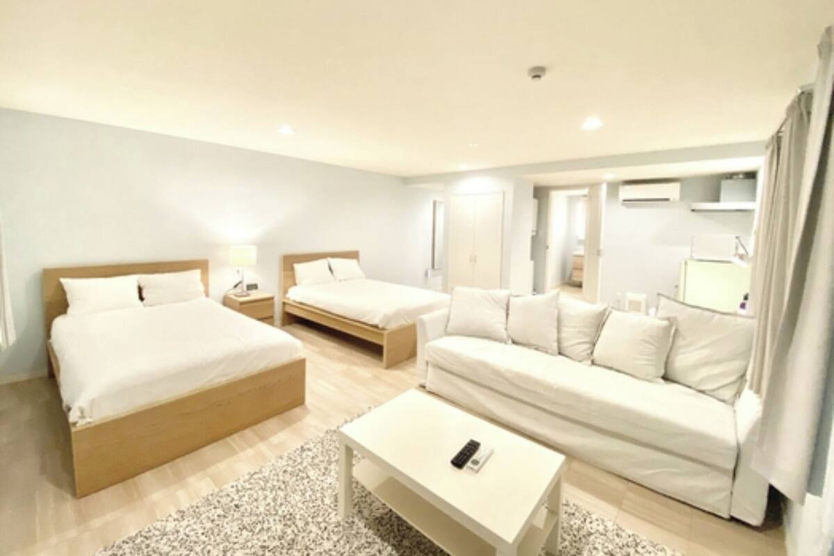 Une chambre d’hôtel avec deux lits simples, un canapé, une petite table et un téléviseur.