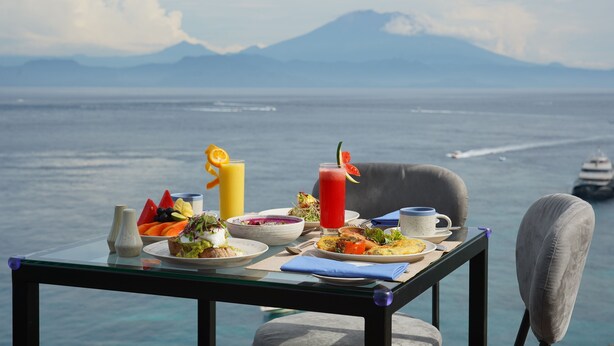 A table with breakfast items and a view of the ocean and mountains. - Adiwana Warnakali Resort (Penida Island)