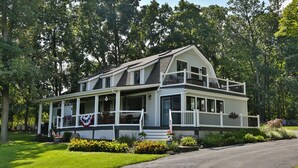 A two-story house with a balcony, surrounded by lush greenery. - Whole House, Scenic Post and Beam Home Overlooking Canandaigua Lake! Sleeps 10 (Canandaigua)