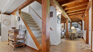 A spacious room with a wooden ceiling, a staircase, a sofa, and a small table. - Whole House, Scenic Post and Beam Home Overlooking Canandaigua Lake! Sleeps 10 (Canandaigua)