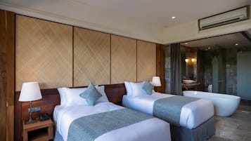 A hotel room with two beds, a large bathtub, and a separate bathroom with a sink and mirror.