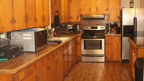 Une cuisine avec des meubles de rangement en bois, une cuisinière, un four à micro-ondes et un réfrigérateur.