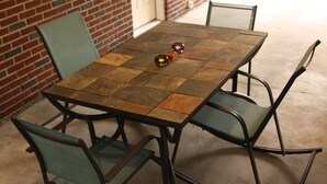 Une table carrée dont le plateau est recouvert de mosaïques, entourée de quatre chaises en métal avec un revêtement vert.