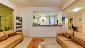 A spacious living room with two leather sofas, a wooden coffee table, a ceiling fan, and a reception desk with a mirror. - Alaya Stays Veera Strand Park (Calangute)