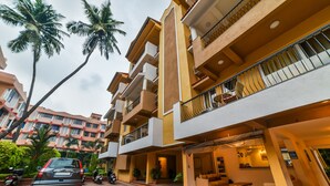 A multi-story hotel with balconies, outdoor seating, and palm trees. - Alaya Stays Veera Strand Park (Calangute)