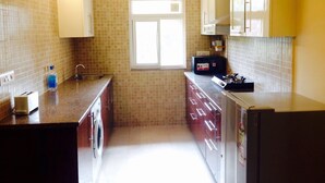 A compact kitchen with a built-in washing machine, a window, and a ceiling fan. - Alaya Stays Veera Strand Park (Calangute)