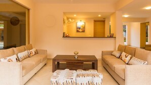 A living room with two sofas, a coffee table, and a large mirror. - Alaya Stays Veera Strand Park (Calangute)