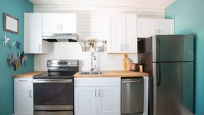 A modern kitchen with white cabinets, stainless steel appliances, and a wooden countertop.