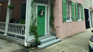 A two-story building with a balcony, a green door, and a security system sign.