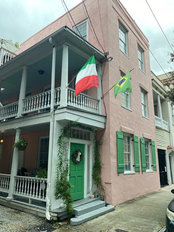 Un edificio de dos pisos con un balcón, una puerta verde y un letrero de sistema de seguridad.