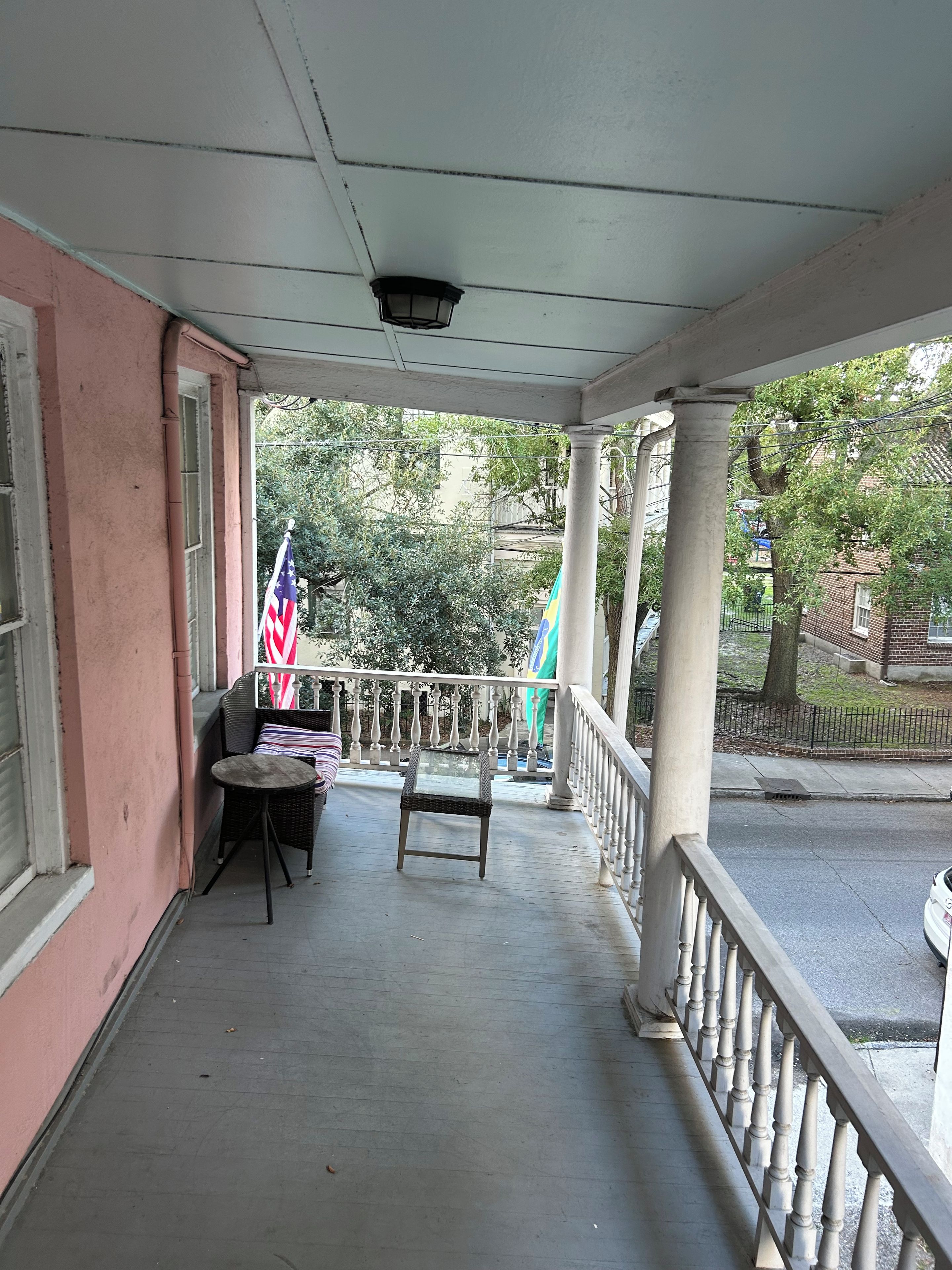 A covered porch with a railing, a table, and two chairs.