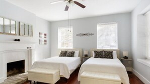 A room with two beds, a fireplace, and a ceiling fan.