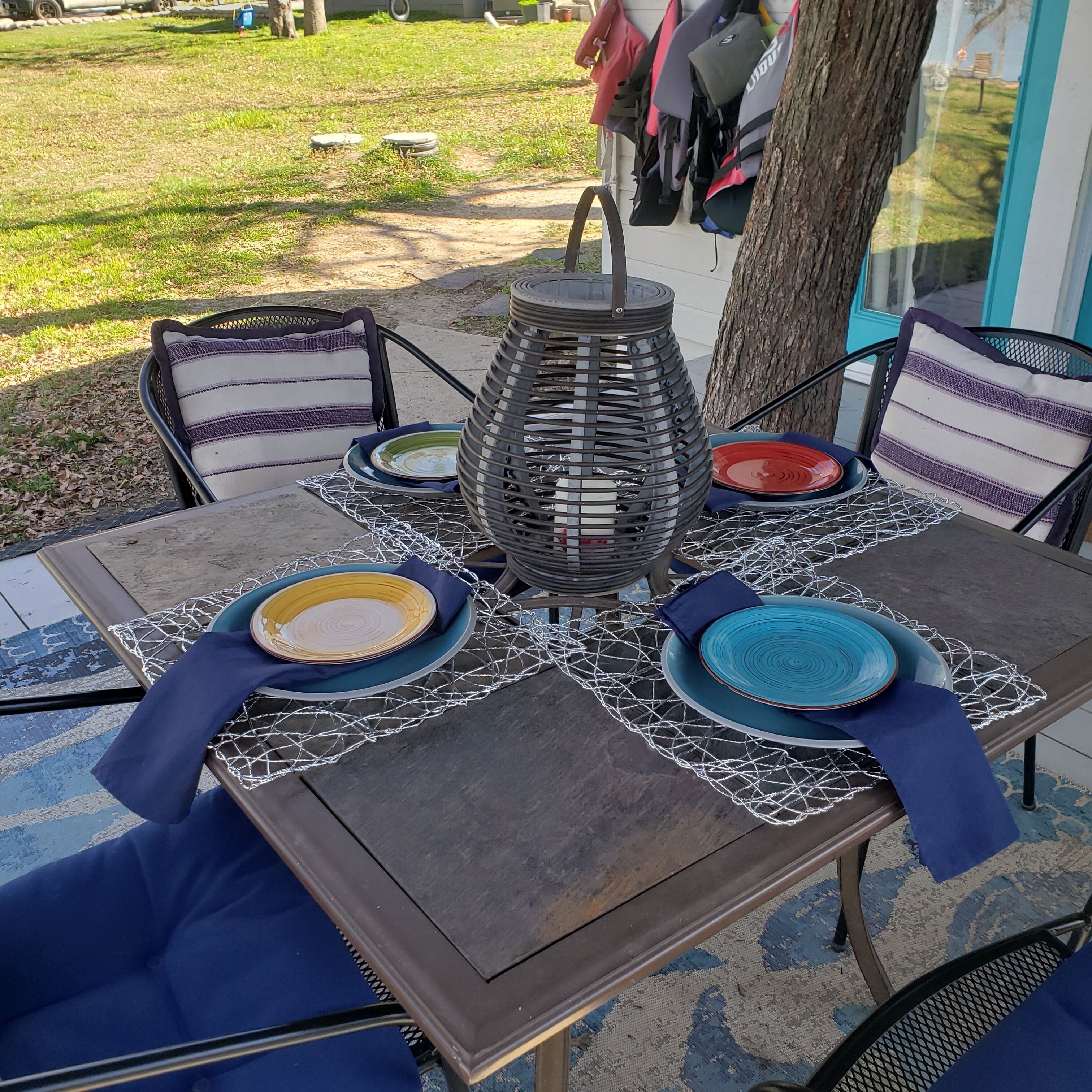 A patio table set with plates, napkins, and a decorative centerpiece.