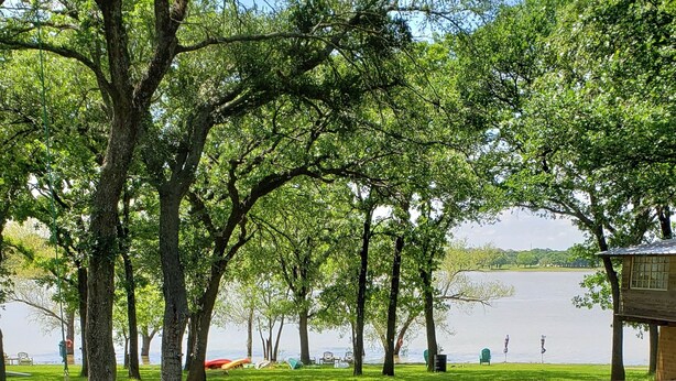 Una terraza de madera con vista a un lago, rodeada de árboles.