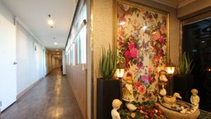A hallway with wooden flooring, a floral wall mural, and decorative statues. - Yangji Park Hotel (Changwon)