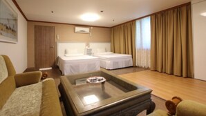 A hotel room with two single beds, a sofa, a coffee table, and a large window with curtains. - Yangji Park Hotel (Changwon)