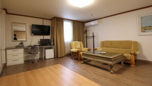 A living room with a sofa, two armchairs, a coffee table, a TV, a desk, and a computer. - Yangji Park Hotel (Changwon)