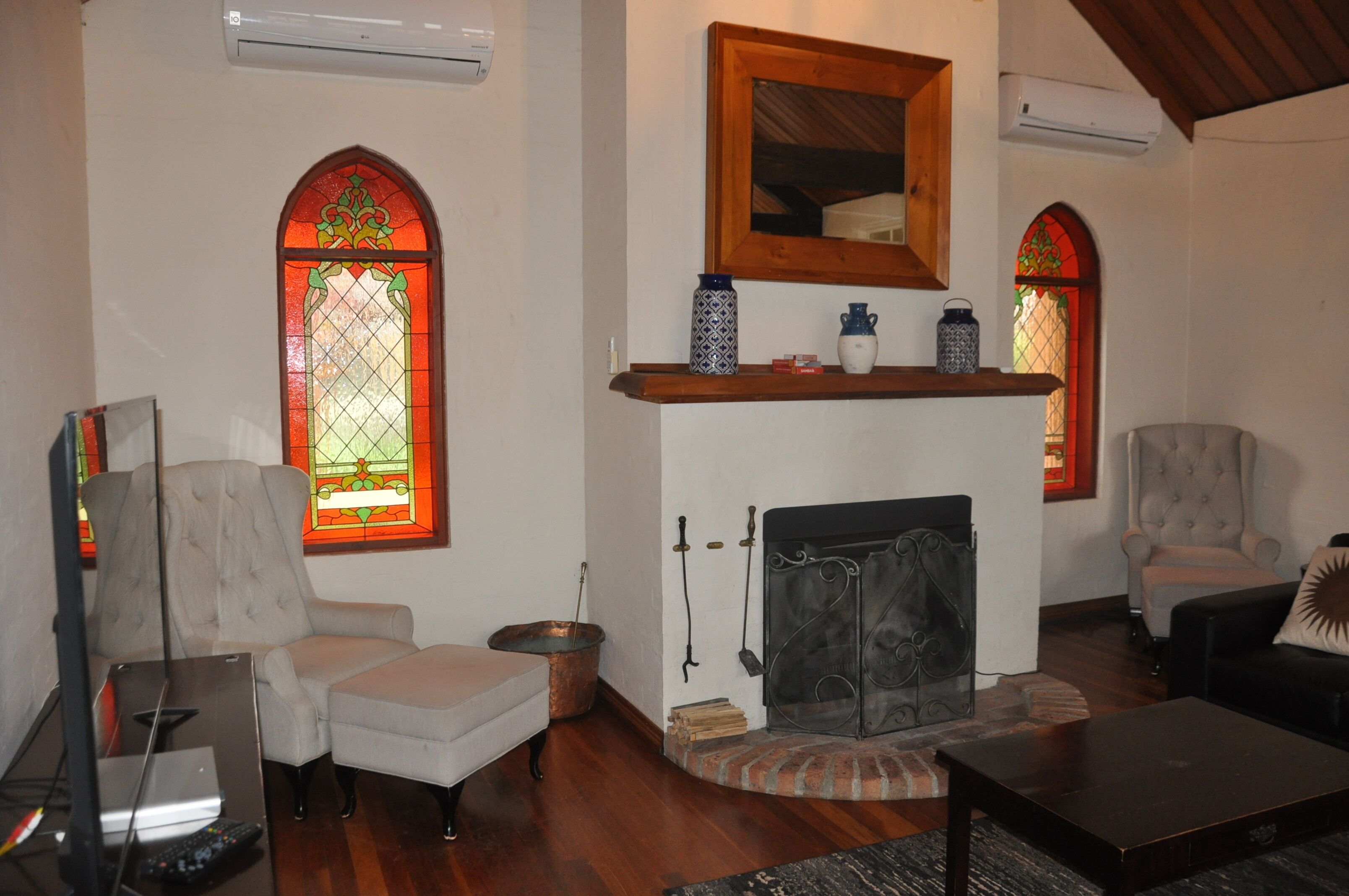 Una sala de estar con chimenea, dos sillones, un televisor y una estantería.