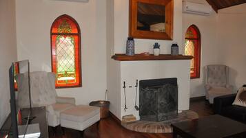 Una sala de estar con chimenea, dos sillones, un televisor y una estantería.