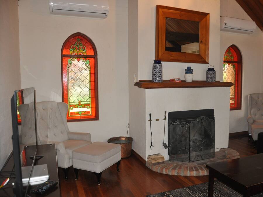Una sala de estar con chimenea, dos sillones, un televisor y una estantería.