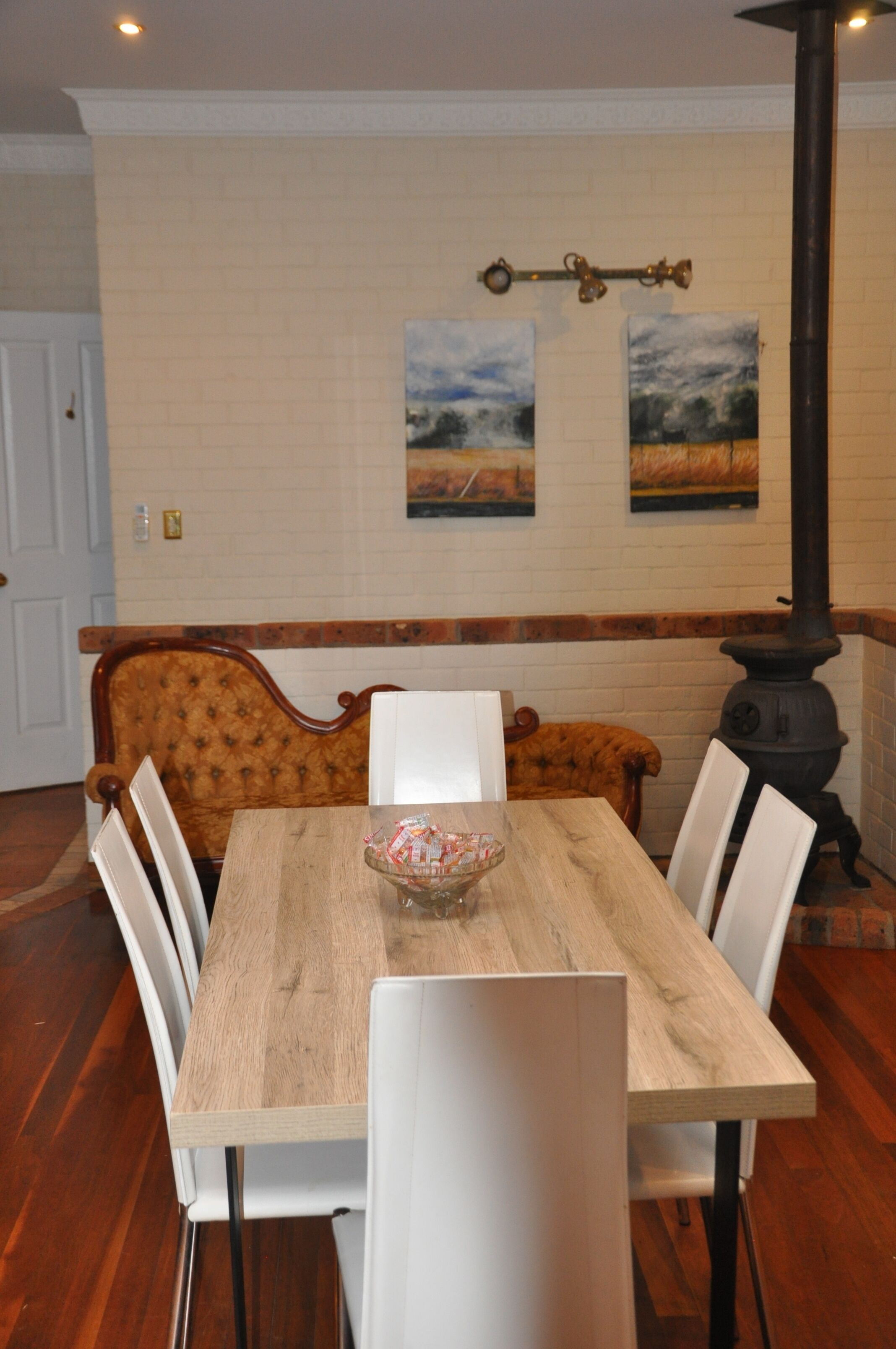 A dining area with a wooden table, white chairs, a bench, and a black stove.