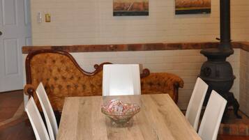 A dining area with a wooden table, white chairs, a bench, and a black stove.