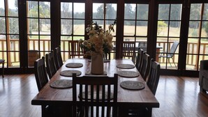 Un comedor con una mesa de madera dispuesta para seis personas, rodeada de sillas, y un jarrón de flores en el centro.