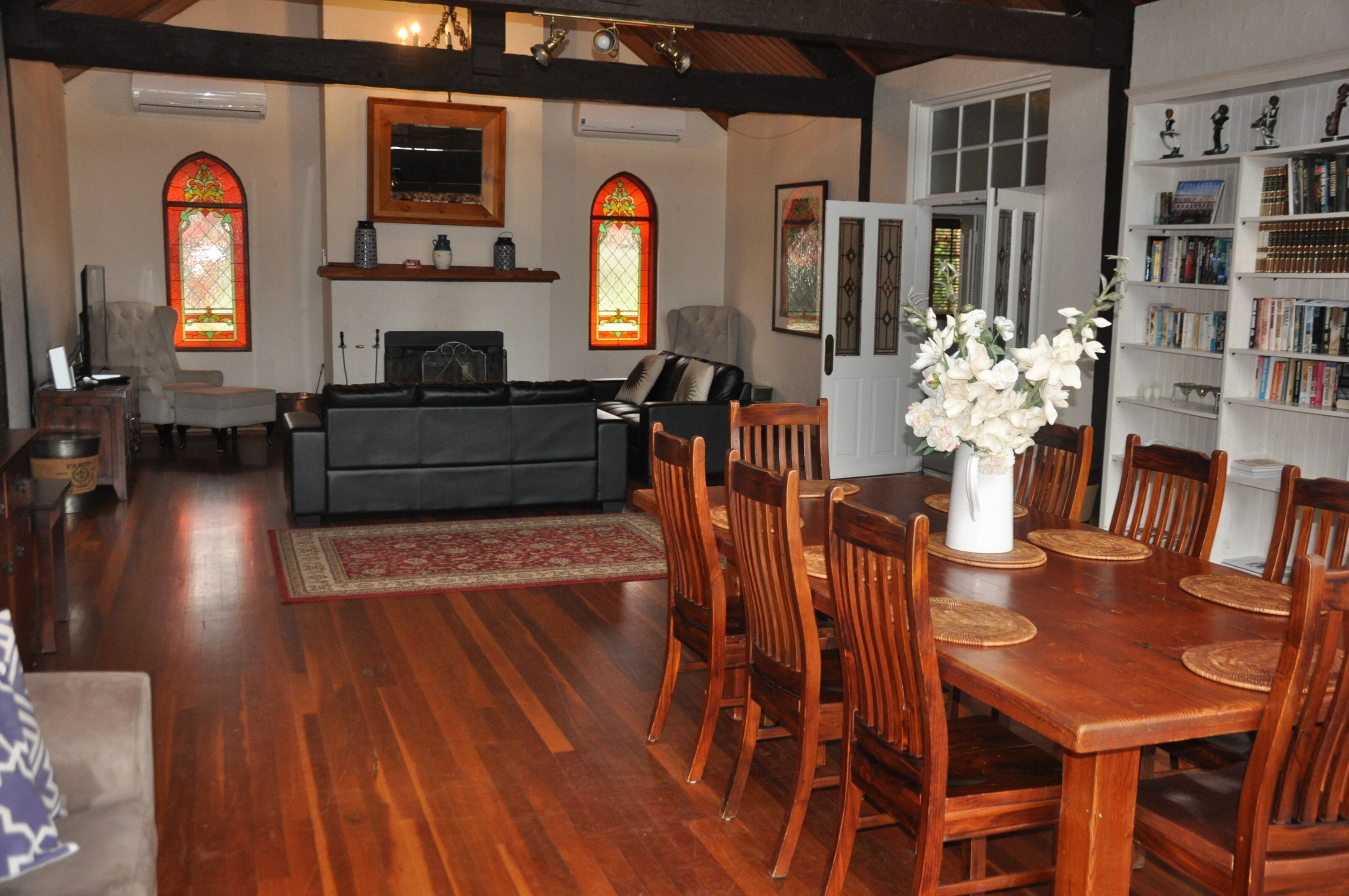A dining area with a wooden table and chairs, a fireplace, and a bookshelf with books.