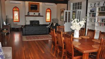 A dining area with a wooden table and chairs, a fireplace, and a bookshelf with books.