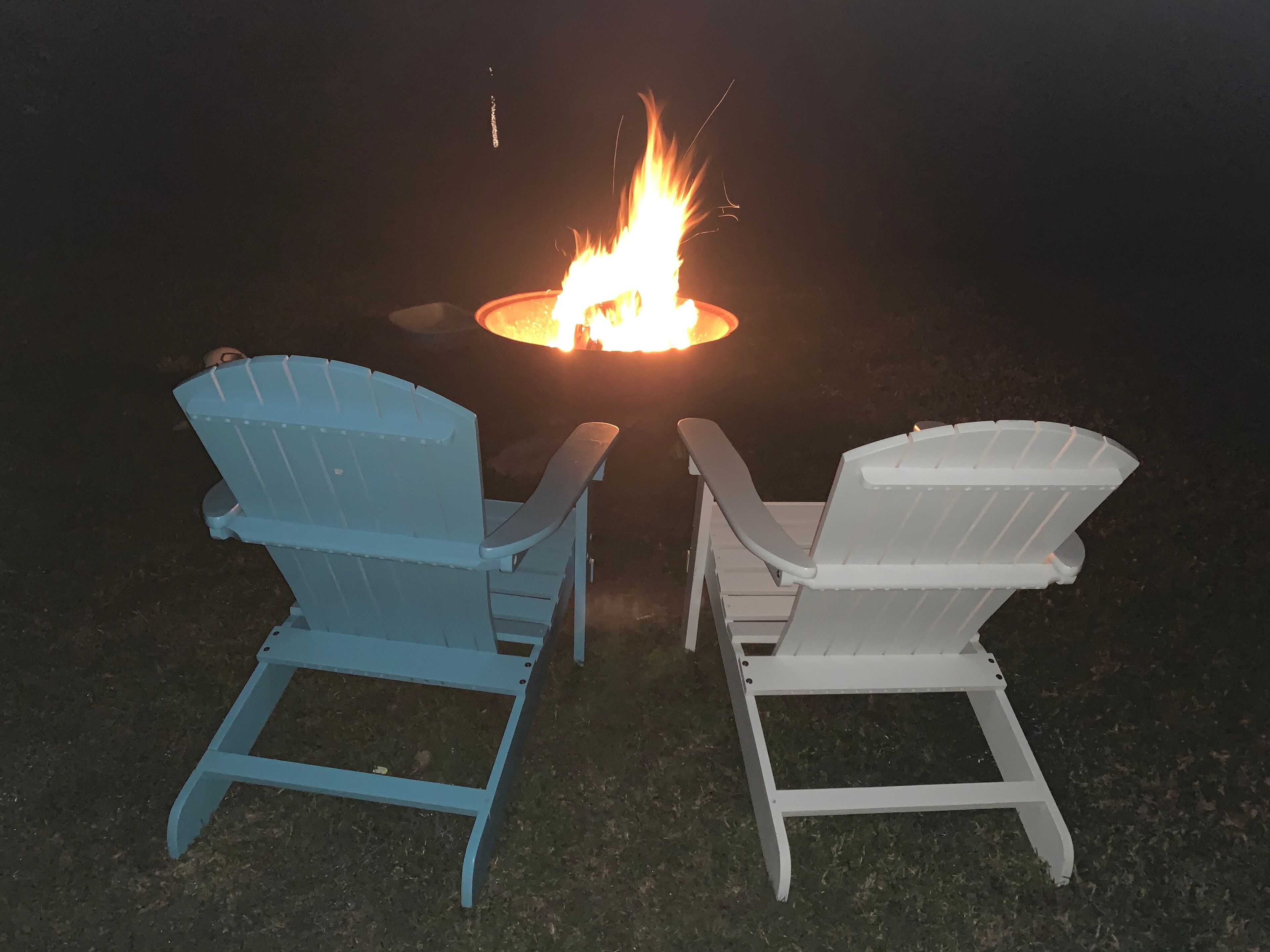 Dos sillas Adirondack mirando hacia una fogata.