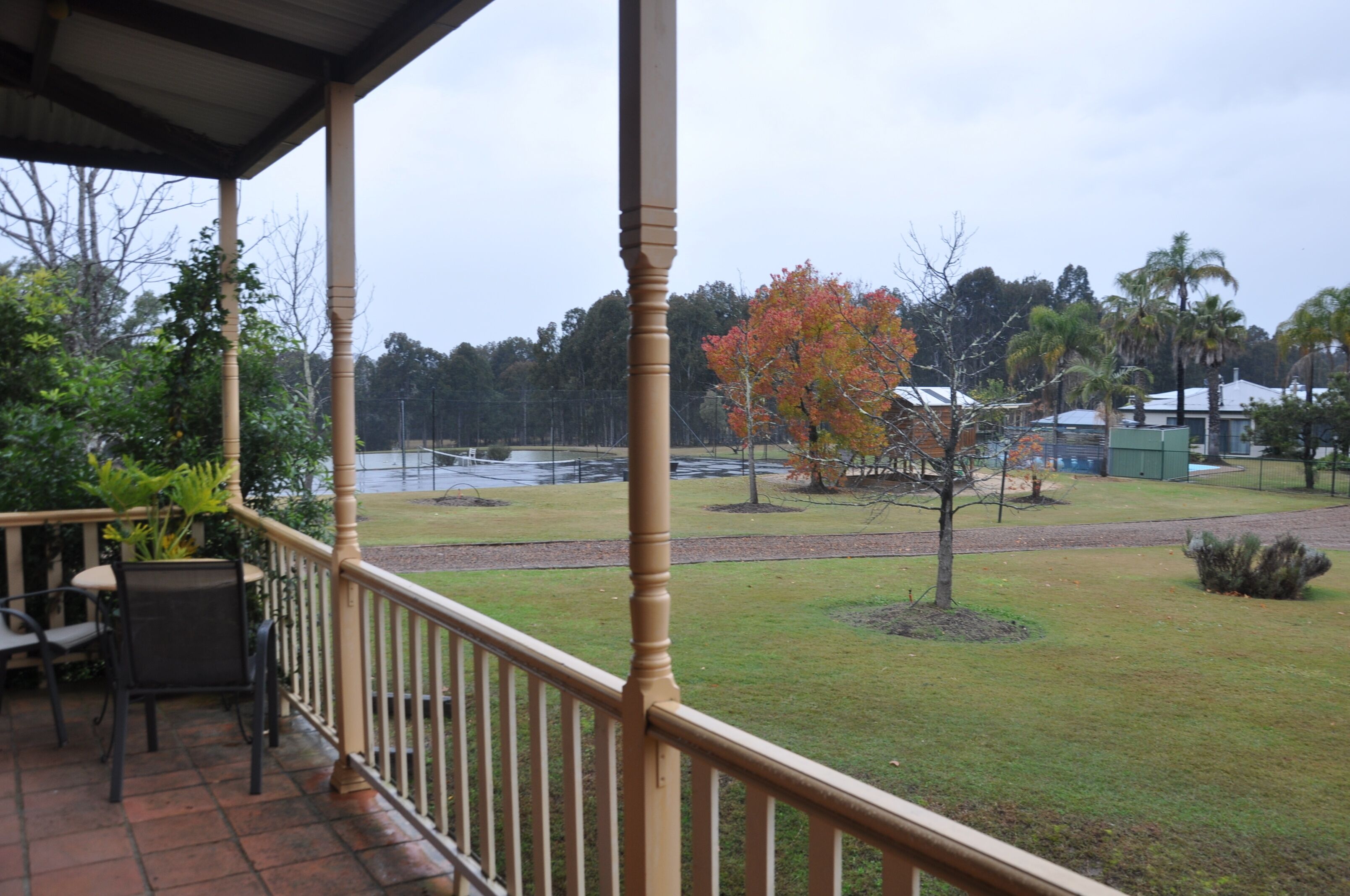 A covered outdoor area with a wooden railing, a table, and chairs.