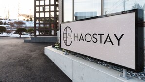 A sign with the word "HAOSTAY" and a logo, placed in front of a building with large windows and a modern design. - HaoSTAY (Fujikawaguchiko)