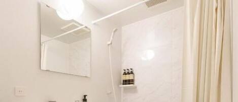Un baño moderno con lavamanos, inodoro y zona de ducha blancos.