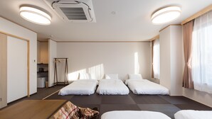 A hotel room with three single beds, a wooden wardrobe, a kitchenette, and a large window with curtains. - HaoSTAY (Fujikawaguchiko)