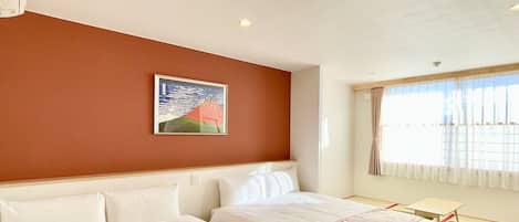 A hotel room with two beds, a painting on the wall, a window with curtains, and a small table.