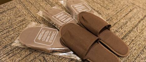 A pair of brown slippers and their packaging on a textured carpet.