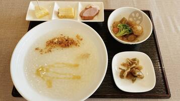 A meal consisting of a large bowl of rice porridge, a smaller bowl of soup with vegetables, and a plate with pickled vegetables.