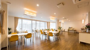 A spacious hotel dining area with multiple tables and chairs, large windows with curtains, and a kitchenette area. - HaoSTAY (Fujikawaguchiko)