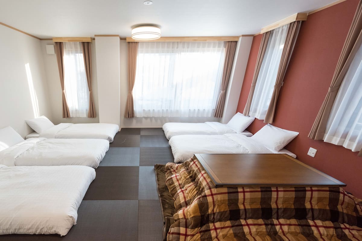 Quarto de hotel com duas camas, uma mesinha e um sofá.