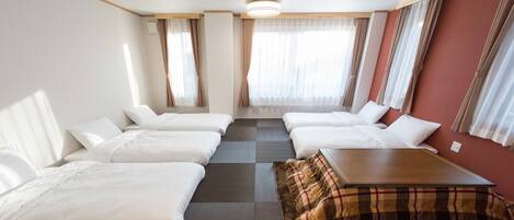 Habitación de hotel con dos camas, una mesita y un sofá.
