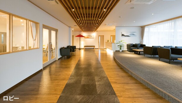 A spacious hallway with wooden flooring, a reception area with seating, and large windows. - HaoSTAY (Fujikawaguchiko)