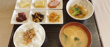 Una bandeja con diferentes platos, incluyendo arroz, sopa y guarniciones variadas.