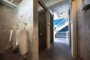 A modern restroom with urinals, a fire extinguisher, and a view of a blue staircase. - Sleep To Fly Hotel & Hostel (Bangkok)