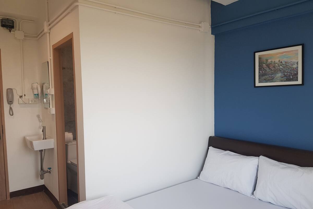 A hotel room with a bed, a bathroom with a sink and mirror, and a painting on the wall.