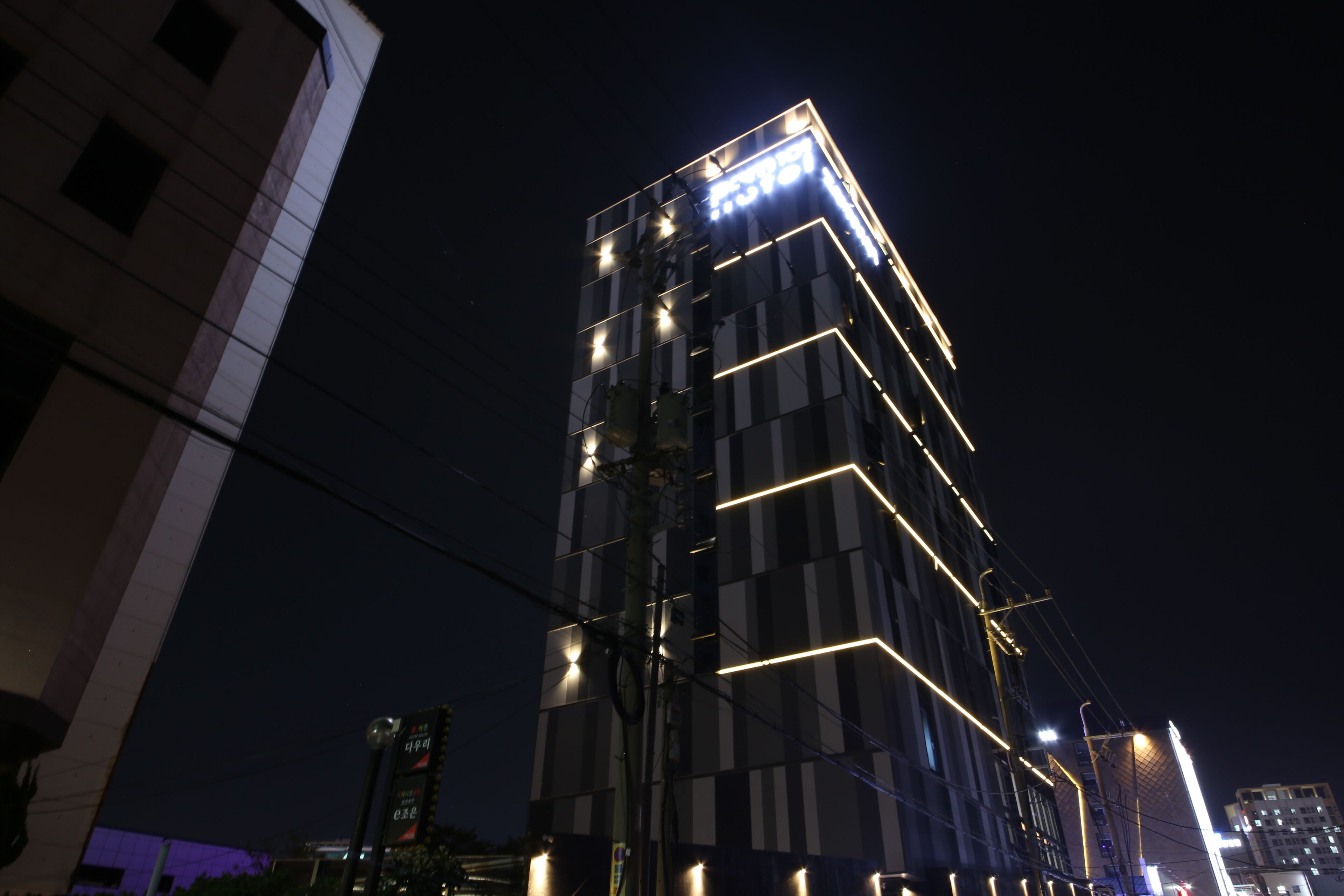 A modern high-rise building with illuminated lines and a digital display at the top.