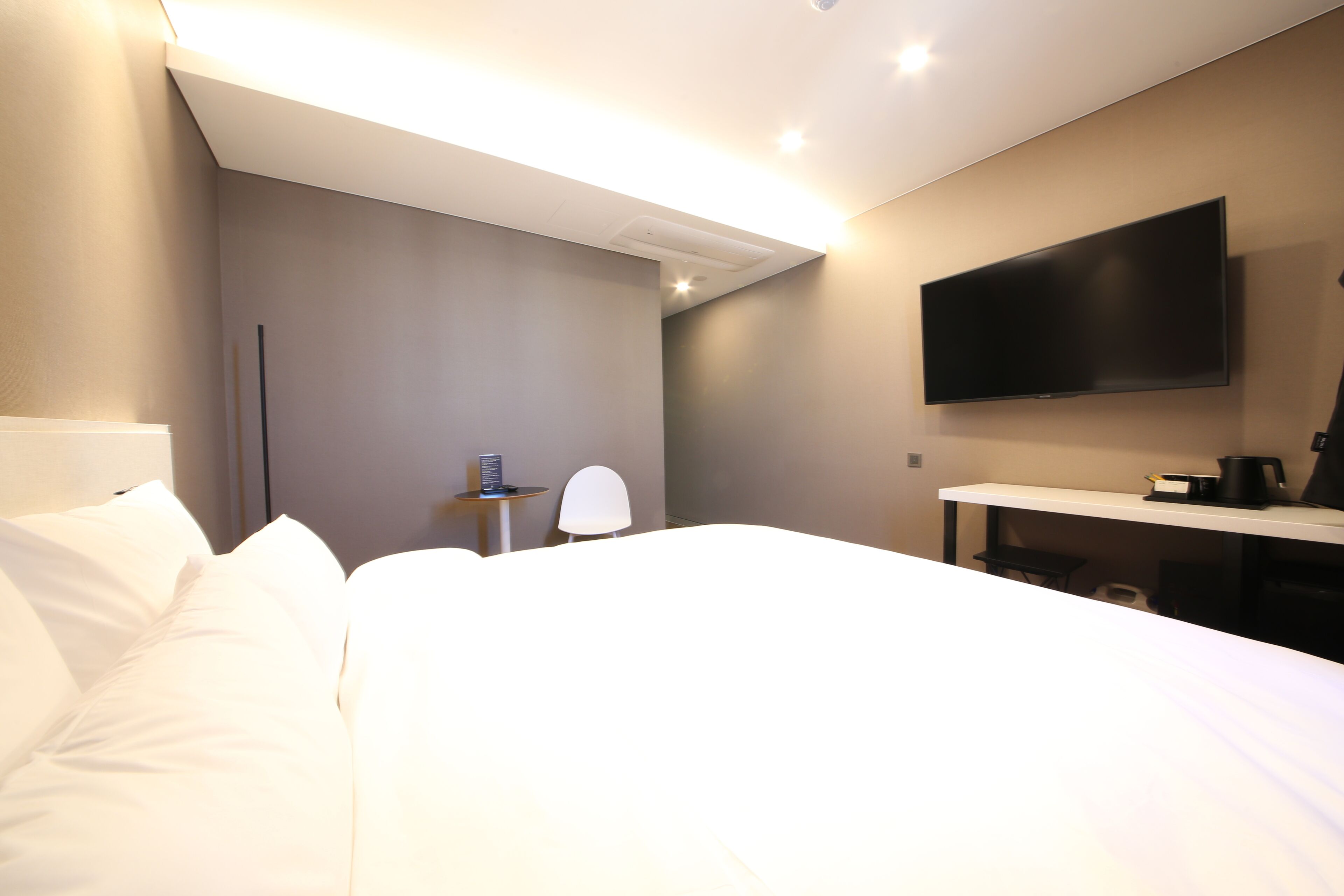 Een hotelkamer met een bed, een bureau, een stoel, een flatscreen televisie en een koffiezetapparaat.