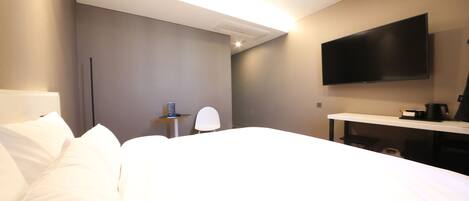 Een hotelkamer met een bed, een bureau, een stoel, een flatscreen televisie en een koffiezetapparaat.